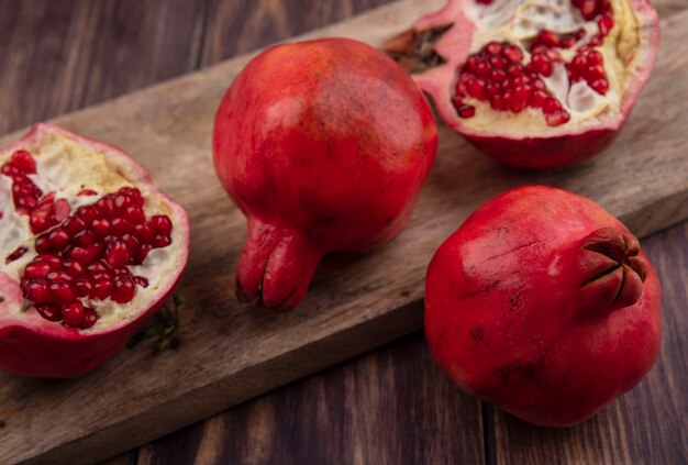 Side view pomegranates on a cutting board on a wooden wall