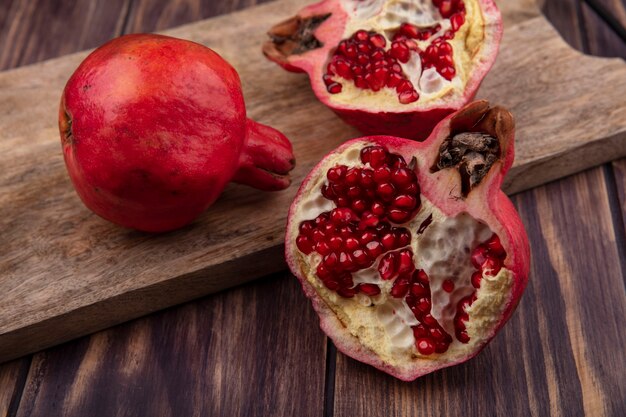 Side view pomegranates on a cutting board on a wooden wall