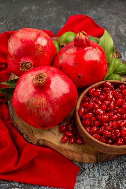 Side view pomegranates seeds of pomegranate three pomegranates with leaves on the wooden board