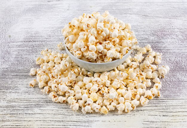 Side view of popcorn in bowl on white wooden  horizontal