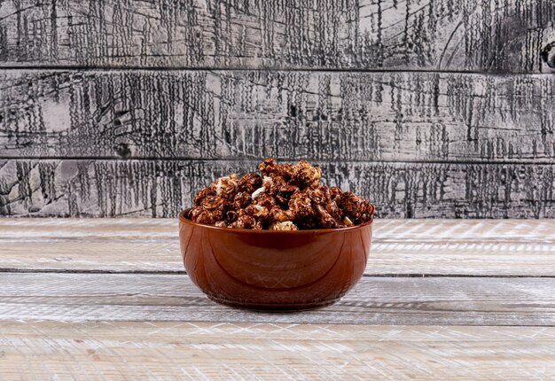 Side view of popcorn in bowl on white wooden table horizontal