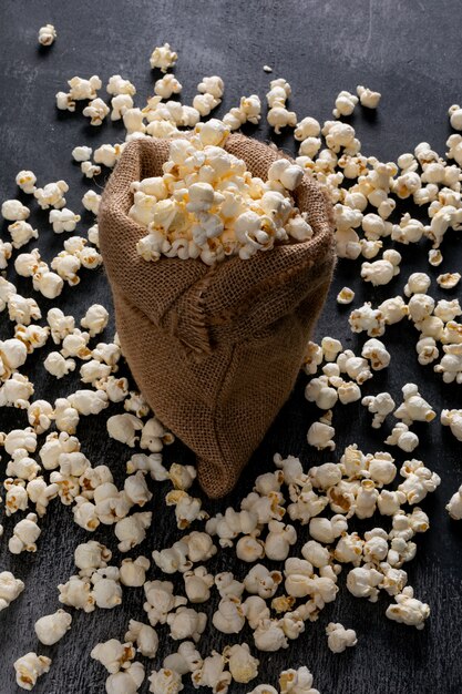 Side view of popcorn in sackcloth bag on black  vertical