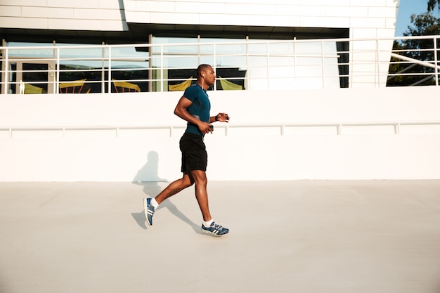 Side view portrait of a african sportsman in earphones running