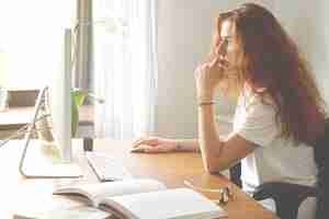 Free photo side view portrait of beautiful young female office worker sitting in front of the computer