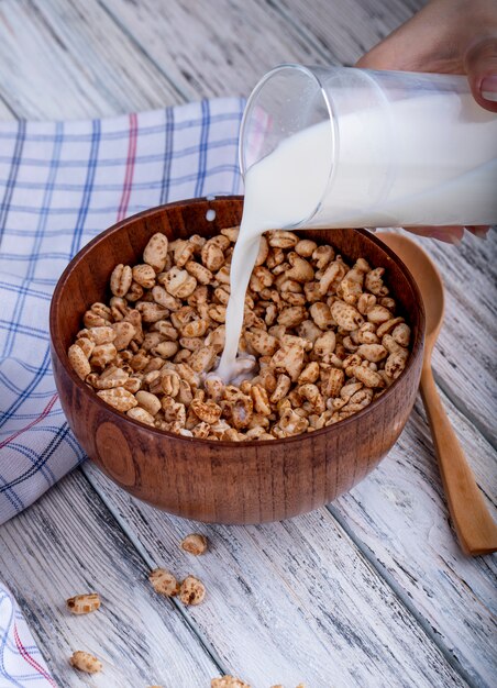 Side view of pouring milk on puffed sweet rice rustic