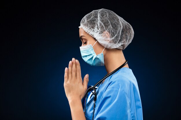 Side view of praying doctor isolated over black