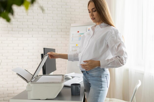 사무실에서 스캐너를 사용하여 임신 사업가의 측면보기