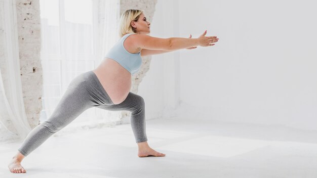 Вид сбоку беременная женщина делает упражнения