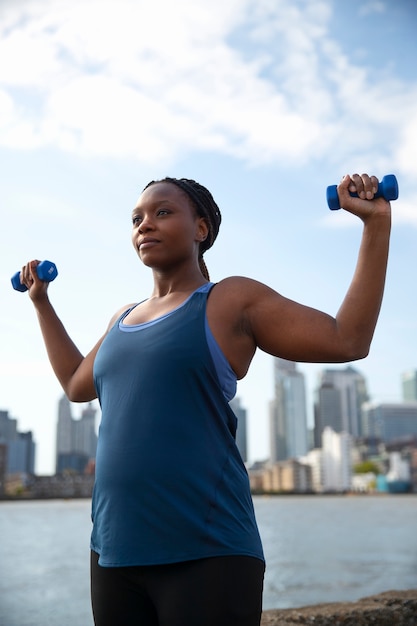 Free photo side view pregnant woman doing sport outdoors