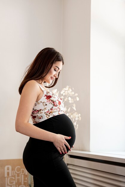 Side view pregnant woman holding her belly