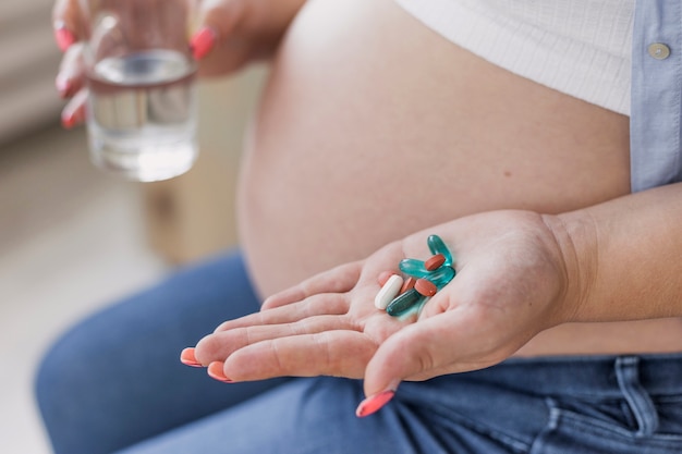 Бесплатное фото Вид сбоку беременная женщина, держащая ее таблетки