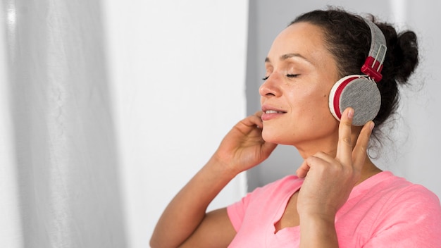 Side view of pregnant woman at home listening to music on headphones