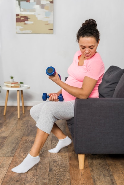 Side view of pregnant woman at home with weights