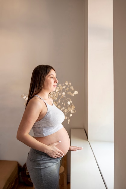 Side view pregnant woman looking out the window