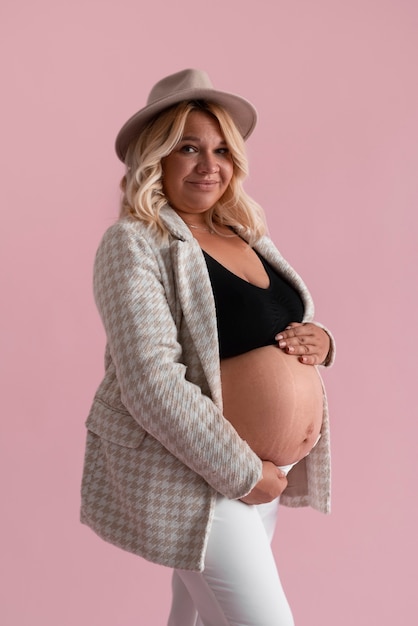 Free photo side view pregnant woman posing in studio