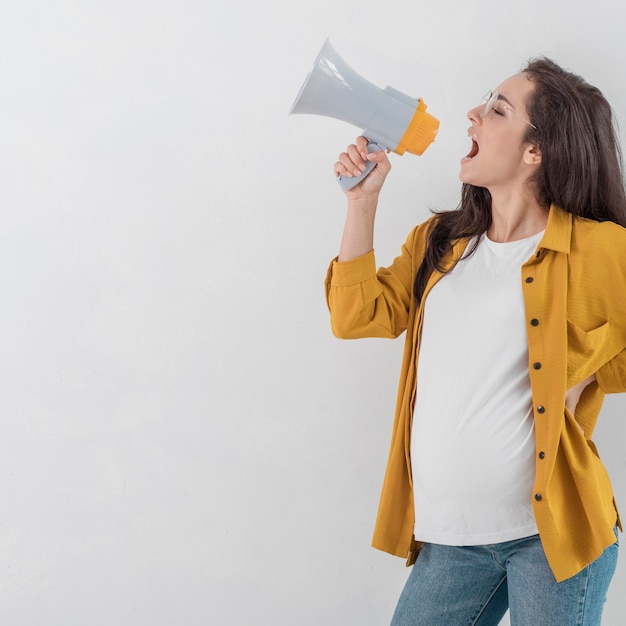 Side view of pregnant woman shouting in megaphone