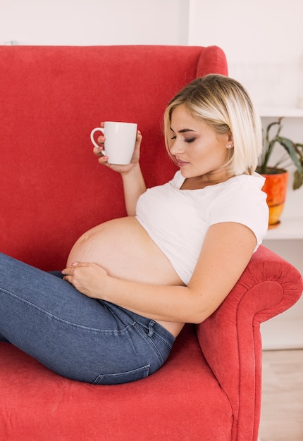 肘掛け椅子に座ってサイドビュー妊娠中の女性