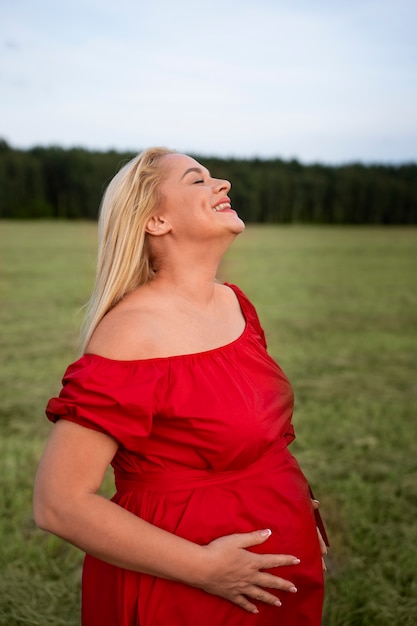 Боковой вид беременная женщина проводит время на открытом воздухе