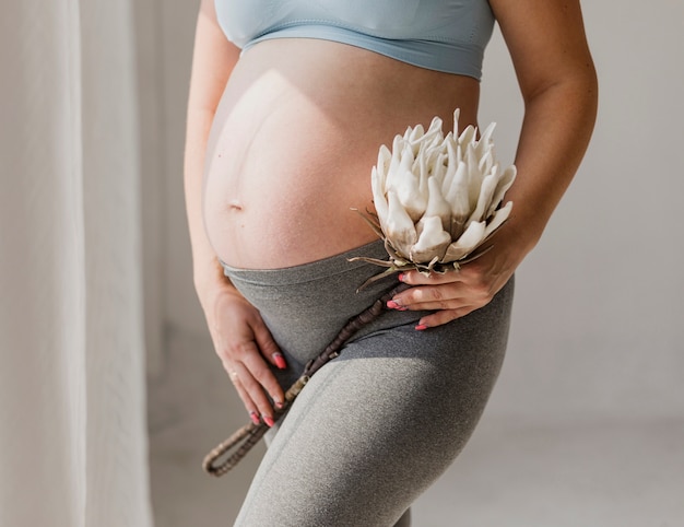 Free photo side view pregnant woman standing next to window