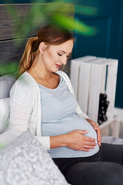 Side view of pregnant woman touching her belly