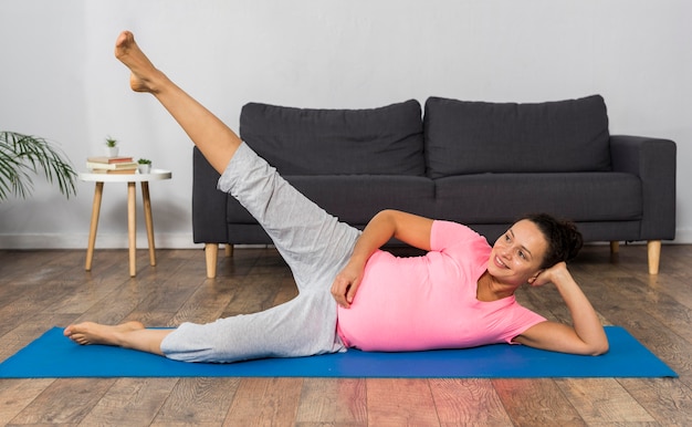 Side view of pregnant woman training on mat at home