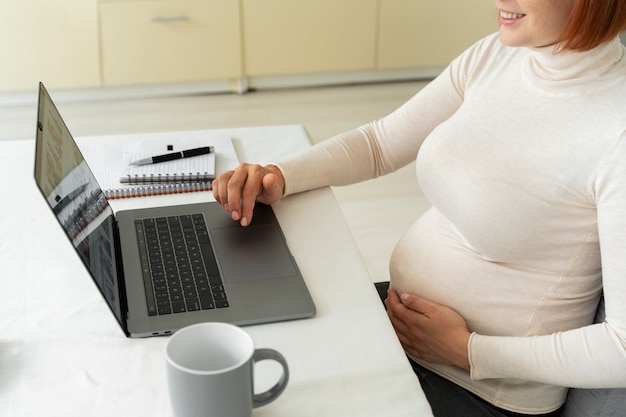 Free photo side view pregnant woman working from home