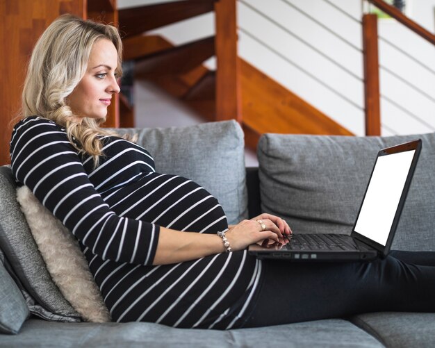 Вид сбоку беременная женщина, работающая на ноутбуке