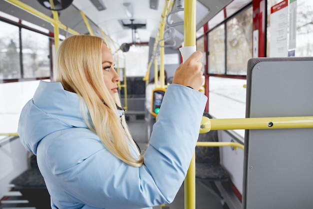 Free photo side view of pretty female wearing blue jacket holding handrail through napkin standing in moving