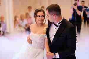 Free photo side view of pretty woman in white gown with deep neckline looking at groom which wearing in elegant black suit and bow