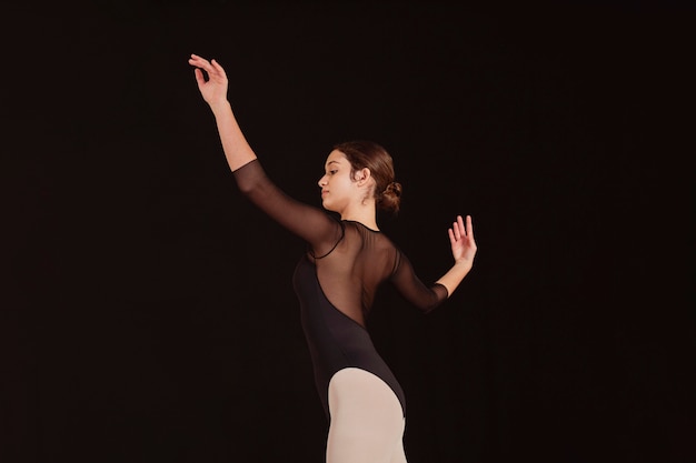 Side view of professional ballet dancer practicing alone