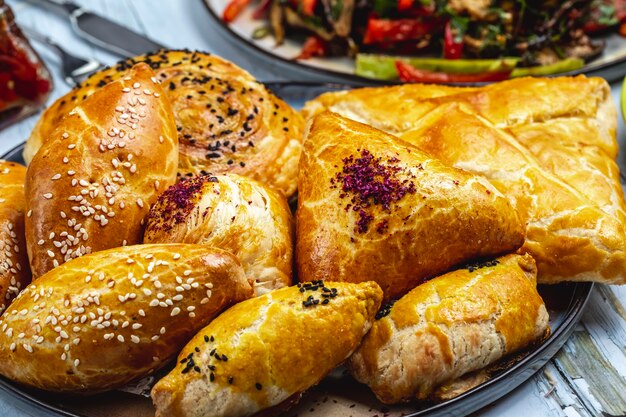 Side view puff pastries with ground meat sesame seeds and shortcakes filled with mashed potato on the table