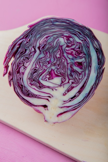 Вид сбоку фиолетовой капусты разрезать пополам на деревянной поверхности и фиолетовом фоне