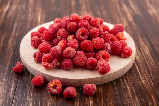 Side view of raspberries on cutting board and on wood