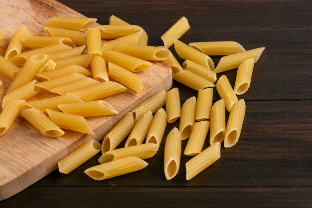 Side view of raw pasta on a cutting board on a wooden surface