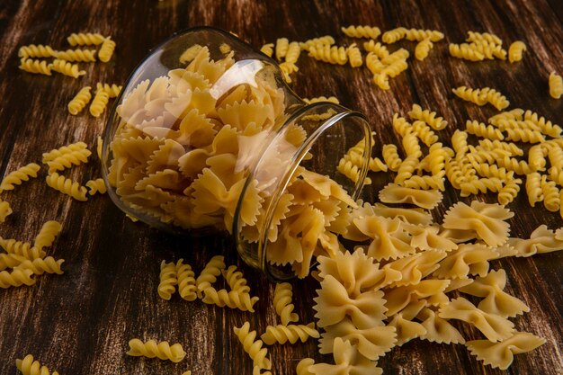 Side view of raw pasta in a jar on a wooden surface
