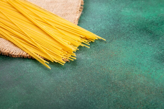 Side view of raw spaghetti on a green surface