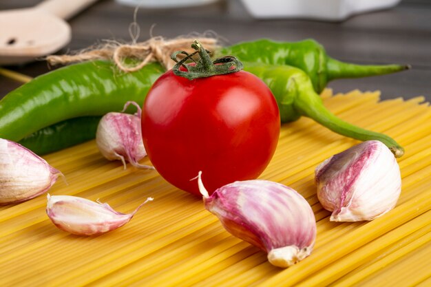 Side view of raw spaghetti with tomato garlic and chili pepper