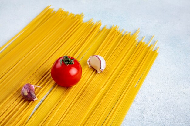 灰色の表面にトマトとニンニクの生スパゲッティの側面図