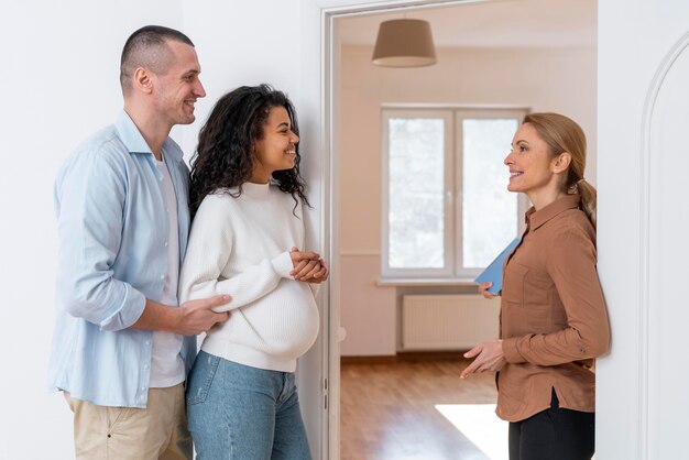Side view of realtor inviting couple in to see new house