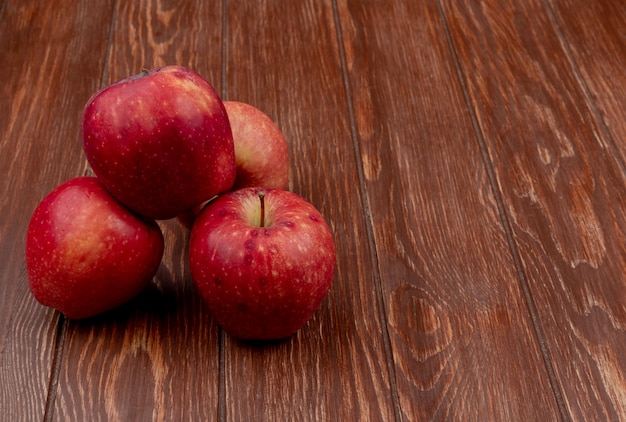 side view of red apples on wooden background with copy space