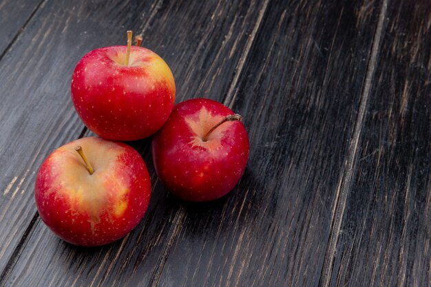 side view of red apples on wooden background with copy space