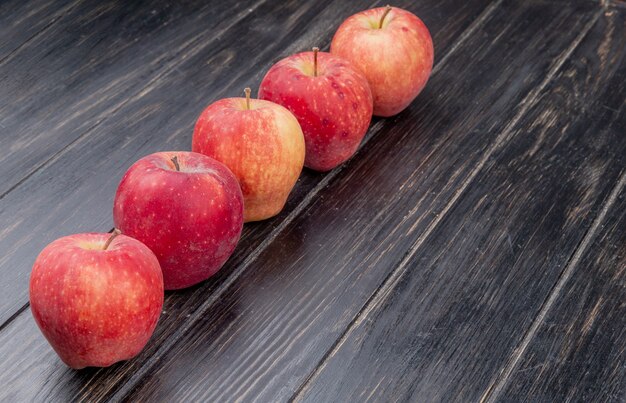 Side view of red apples on wooden surface with copy space