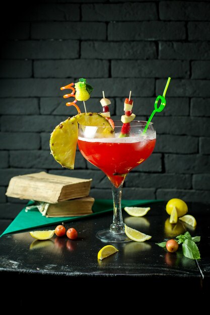 Side view of red exotic alcohol cocktail with a piece on pineapple in glass on the table