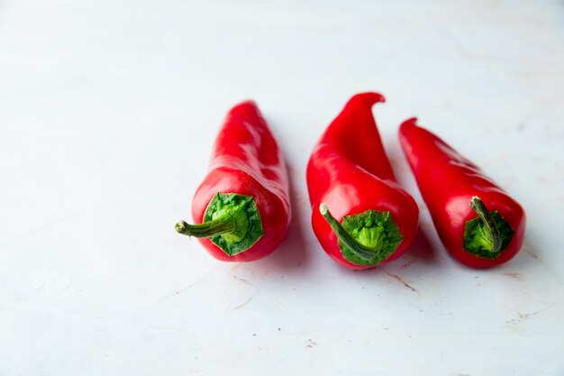Side view of red peppers on right side on white background with copy space