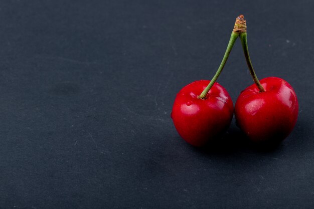 Side view of red ripe cherry isolated on black with copy space