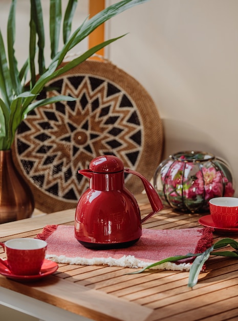 Side view of red tea set of cups and teapot on a wooden table