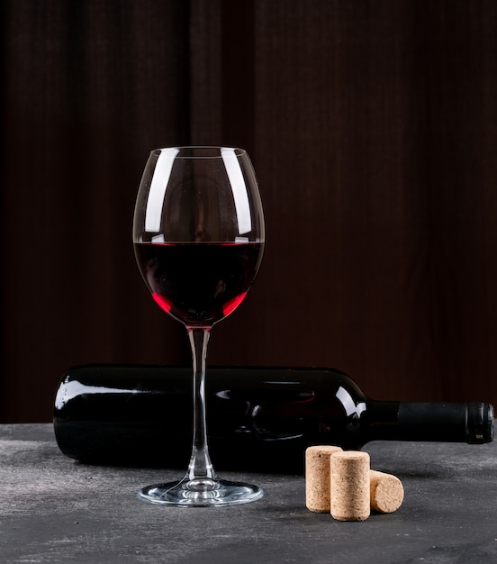 Вид сбоку красное вино на черной вертикали