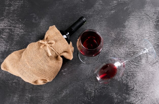 Side view red wine bottle in sackcloth bag on black stone horizontal