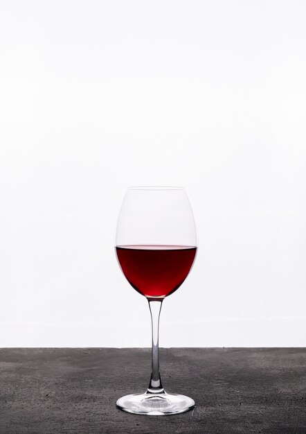 Вид сбоку красное вино в бокале на белой вертикали