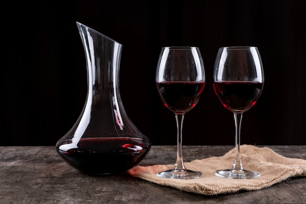 Side view red wine in glasses and linen cloth on dark horizontal